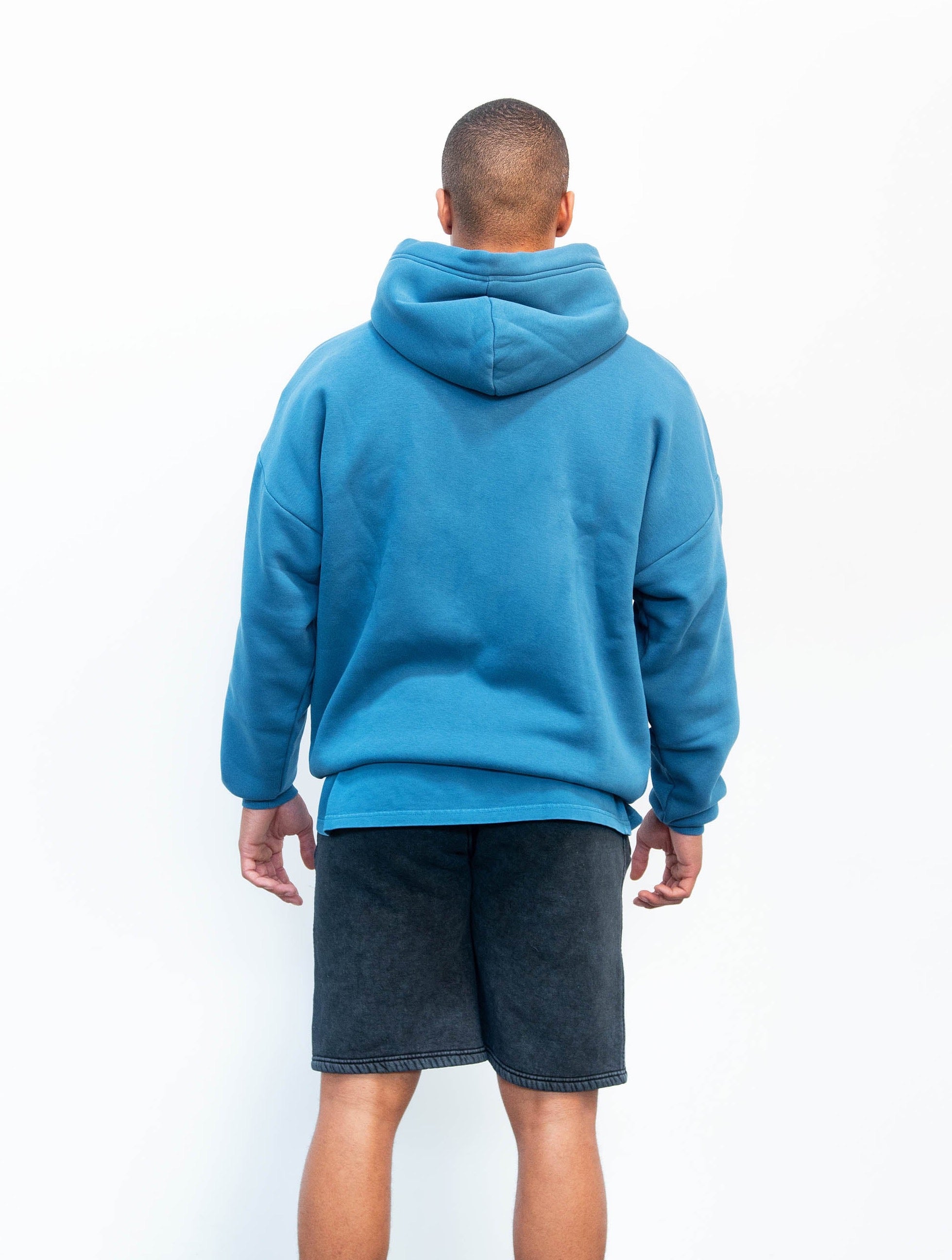 Back view of model wearing blank hoodie in midnight blue