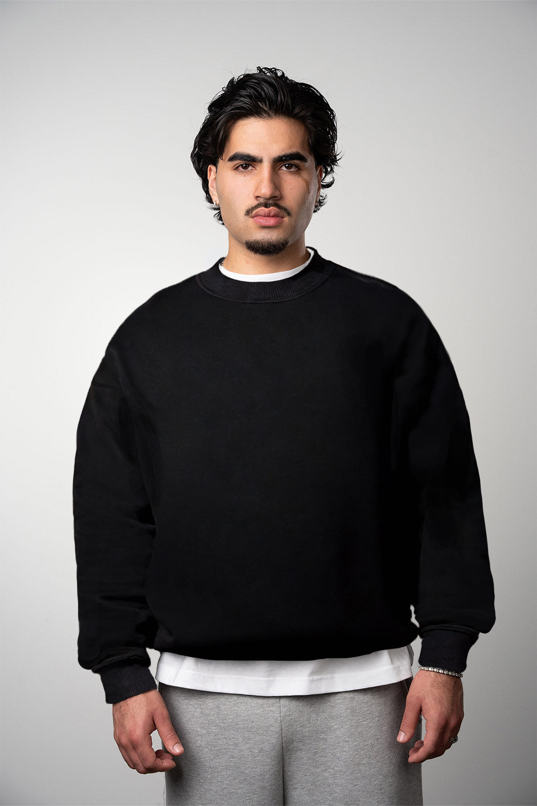 A male model is wearing the black LEMUTA Blank Sweater with no branding or labeling