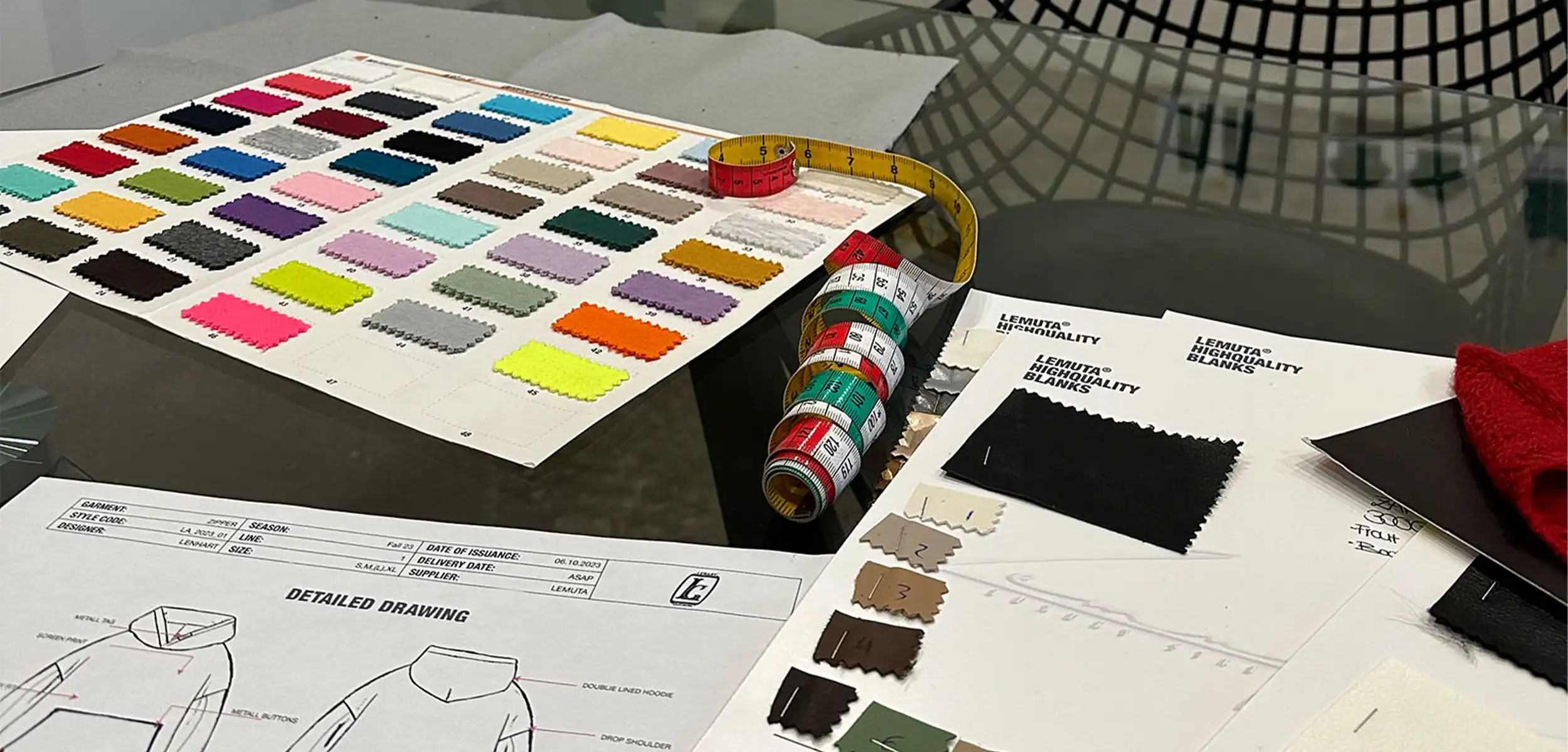 Printed Tech Packs, measuring tape and fabrics on a table