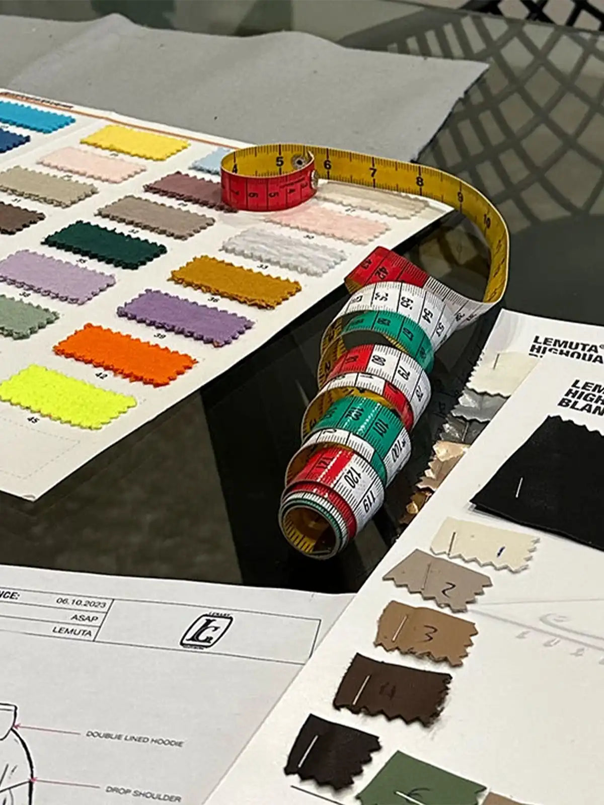 Printed Tech Packs, measuring tape and fabrics on a table